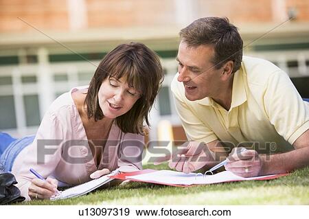 Adult students lying on lawn of school studying and talking View Large Photo Image Stock Photo - Adult students lying on lawn of school studying and talking. Fotosearch