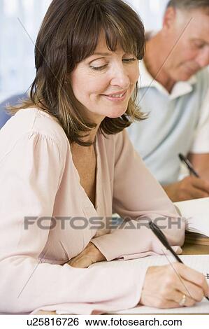Stock Photograph - Adult students studying at table (selective focus). Fotosearch