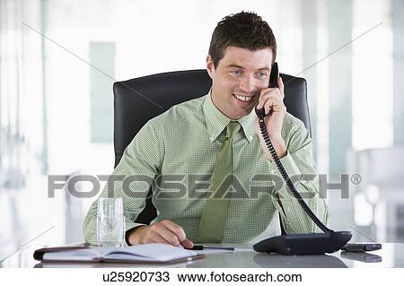 Businessman sitting in office with personal organizer on telephone View Large Photo Image Stock Image - Businessman sitting in office with personal organizer on telephone. Fotosearch