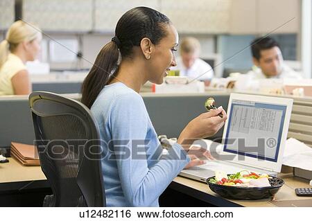 Businesswoman in cubicle eating sushi smiling View Large Photo Image Stock Photograph - Businesswoman in cubicle eating sushi smiling. Fotosearch