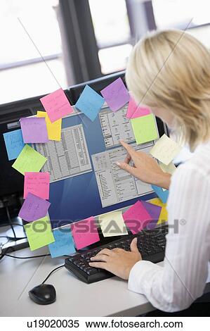 Businesswoman in office pointing at monitor with notes on it View Large Photo Image Stock Photography - Businesswoman in office pointing at monitor with notes on it. Fotosearch