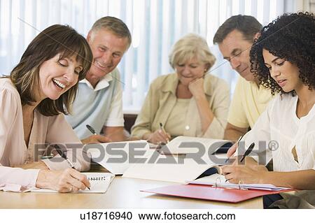 Stock Image - Five adult students studying at table (depth of field). Fotosearch