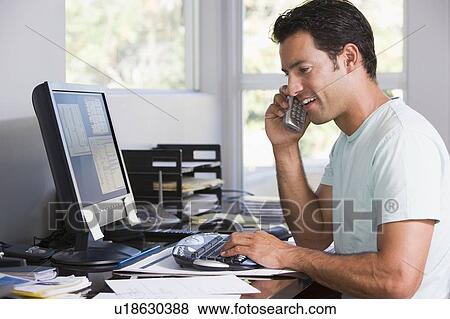 Man in home office on telephone using computer and smiling View Large Photo Image Stock Photo - Man in home office on telephone using computer and smiling. Fotosearch