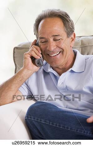 Stock Photography - Man indoors using telephone smiling. Fotosearch