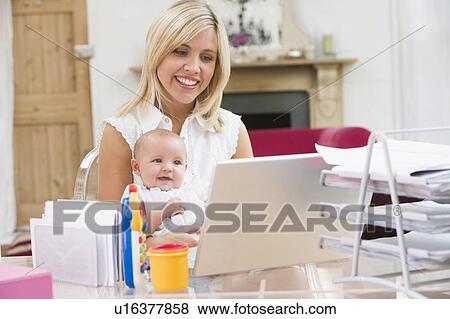 Stock Photo - Mother and baby in home office with laptop. Fotosearch