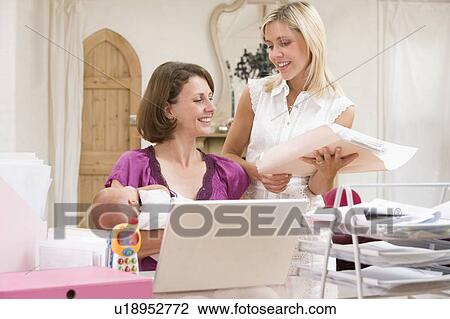 Stock Image - Two women and a baby in home office with laptop. Fotosearch