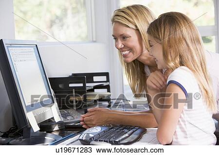 Stock Image - Woman and young girl in home office with computer smiling. Fotosearch