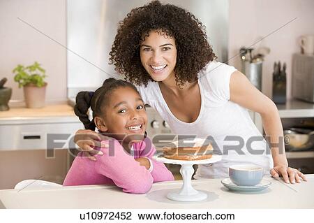 Woman and young girl in kitchen with cake and coffee smiling View Large Photo Image Stock Image - Woman and young girl in kitchen with cake and coffee smiling. Fotosearch