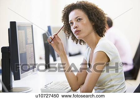 Stock Image - Woman in computer room thinking. Fotosearch