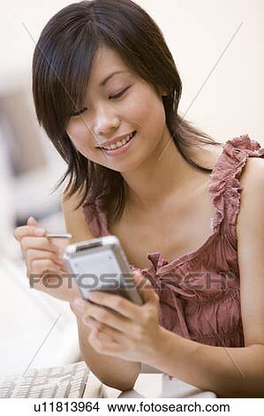 Picture - Woman in computer room using personal digital assistant smiling. Fotosearch