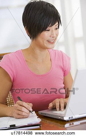 Woman in dining room with laptop smiling View Large Photo Image Stock Photo - Woman in dining room with laptop smiling. Fotosearch