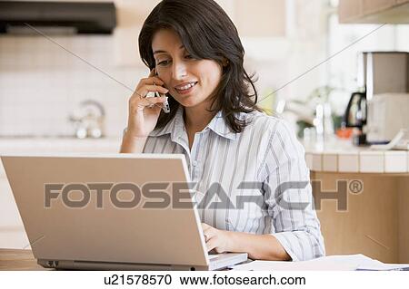 Woman in kitchen with laptop using cellular phone smiling View Large Photo Image Stock Image - Woman in kitchen with laptop using cellular phone smiling. Fotosearch
