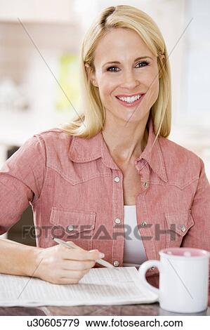 Woman in kitchen with newspaper and coffee smiling View Large Photo Image Stock Photo - Woman in kitchen with newspaper and coffee smiling. Fotosearch