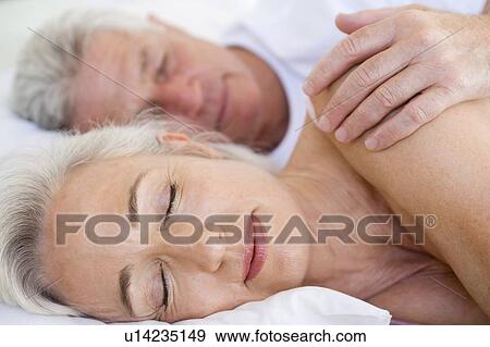 Stock Photo - Couple lying in bed together sleeping. Fotosearch