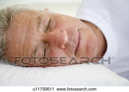 Stock Image - Man lying in bed sleeping. Fotosearch