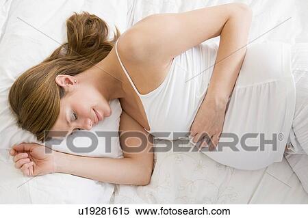Stock Photography - Pregnant woman lying in bed sleeping. Fotosearch
