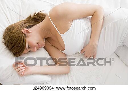 Pregnant woman lying in bed smiling View Large Photo Image Picture - Pregnant woman lying in bed smiling. Fotosearch
