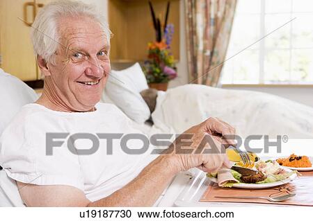 Stock Image - Senior Man Eating Hospital Food In Bad. Fotosearch
