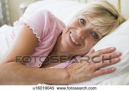 Woman lying in bed smiling View Large Photo Image Stock Photography - Woman lying in bed smiling. Fotosearch