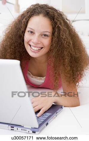 Woman lying in bed with laptop smiling View Large Photo Image Stock Image - Woman lying in bed with laptop smiling. Fotosearch