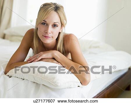 Stock Photo - Woman lying in bedroom smiling. Fotosearch