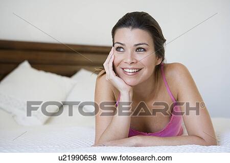 Woman relaxing on bed in bedroom smiling (selective focus) View Large Photo Image Stock Photo - Woman relaxing on bed in bedroom smiling (selective focus). Fotosearch
