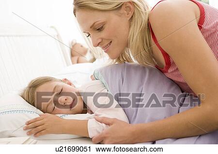 Woman waking young girl in bed smiling View Large Photo Image Stock Image - Woman waking young girl in bed smiling. Fotosearch