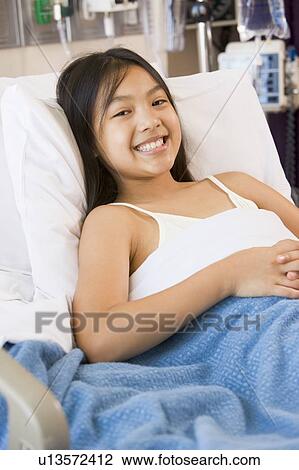 Stock Image - Young Girl Smiling, Lying In Hospital Bed. Fotosearch
