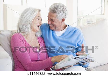 Stock Image - Couple with a magazine smiling. Fotosearch