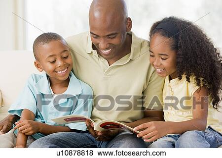 Man and two children sitting in living room reading book and smiling View Large Photo Image Stock Photo - Man and two children sitting in living room reading book and smiling. Fotosearch