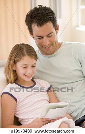 Man and young girl in living room reading book and smiling View Large Photo Image Stock Photo - Man and young girl in living room reading book and smiling. Fotosearch