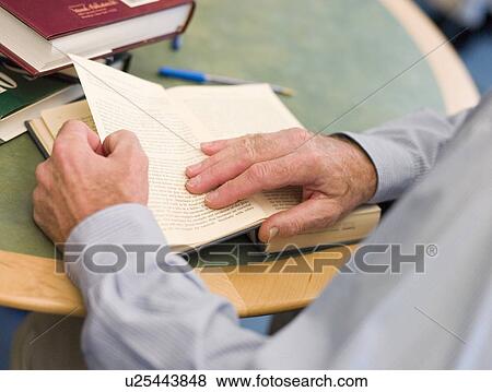 Stock Photo - Man at table reading a book (selective focus). Fotosearch
