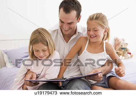 Man in bedroom with two young girls reading book and smiling View Large Photo Image Stock Image - Man in bedroom with two young girls reading book and smiling. Fotosearch