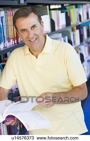 Man in library holding book (depth of field) View Large Photo Image Stock Image - Man in library holding book (depth of field). Fotosearch