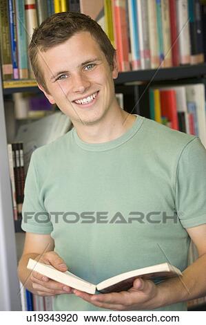 Stock Image - Man in library holding book. Fotosearch
