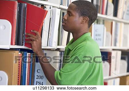 Man In Library Pulling Book Off A Shelf Depth Of Field Stock Image U Fotosearch