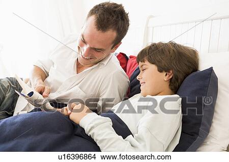 Picture - Man reading book to young boy in bed smiling. Fotosearch
