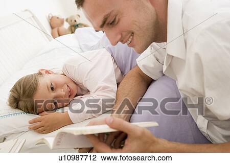 Man reading book to young girl in bed smiling View Large Photo Image Stock Image - Man reading book to young girl in bed smiling. Fotosearch