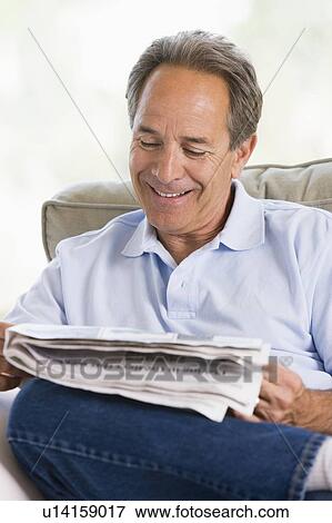 Man relaxing with a newspaper smiling View Large Photo Image Stock Photo - Man relaxing with a newspaper smiling. Fotosearch