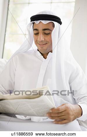 Man sitting indoors with newspaper smiling (high key/selective focus) View Large Photo Image Stock Photo - Man sitting indoors with newspaper smiling (high key/selective focus). Fotosearch