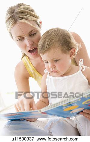 Mother and baby reading book indoors and pointing View Large Photo Image Stock Photo - Mother and baby reading book indoors and pointing. Fotosearch
