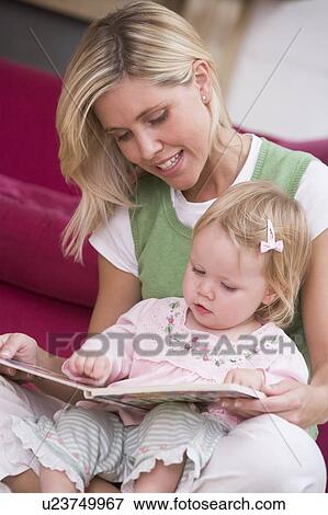Stock Photo - Mother in living room reading book with baby smiling. Fotosearch