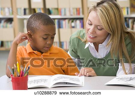 Stock Photo - Student in class reading with teacher. Fotosearch
