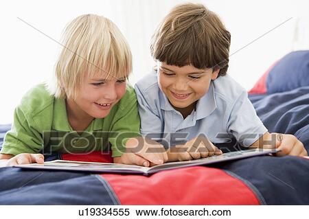 Two Young Boys Lying Down On A Bed Reading A Book View Large Photo Image Stock Photography - Two Young Boys Lying Down On A Bed Reading A Book. Fotosearch