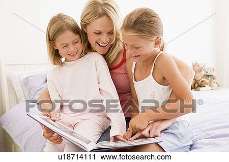 Woman and two young girls in bedroom reading book and smiling View Large Photo Image Stock Image - Woman and two young girls in bedroom reading book and smiling. Fotosearch