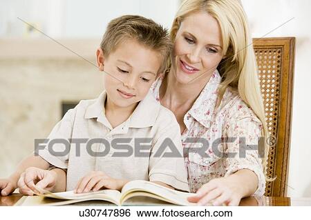 Woman and young boy reading book in dining room smiling View Large Photo Image Stock Photograph - Woman and young boy reading book in dining room smiling. Fotosearch