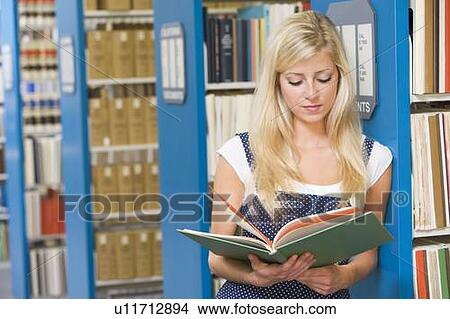 Picture - Woman in library reading book (depth of field). Fotosearch
