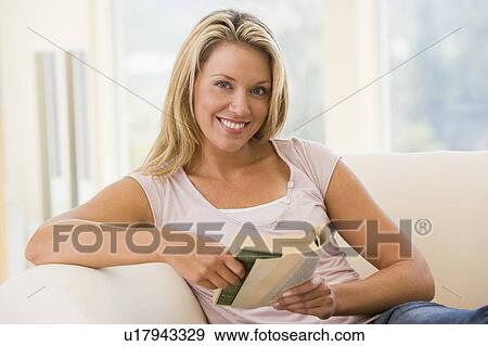 Woman in living room reading book smiling View Large Photo Image Stock Photo - Woman in living room reading book smiling. Fotosearch