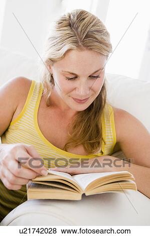 Stock Photo - Woman in living room reading book. Fotosearch