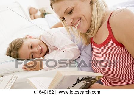 Woman reading book to young girl in bed smiling View Large Photo Image Stock Image - Woman reading book to young girl in bed smiling. Fotosearch